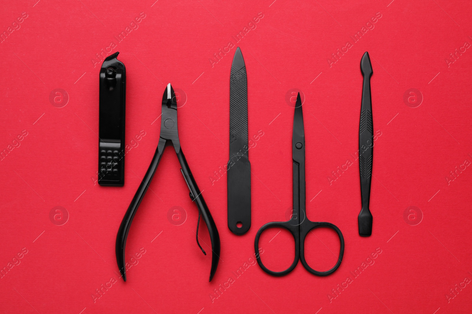 Photo of Set of pedicure tools on red background, flat lay