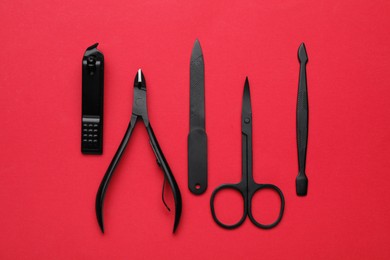 Photo of Set of pedicure tools on red background, flat lay
