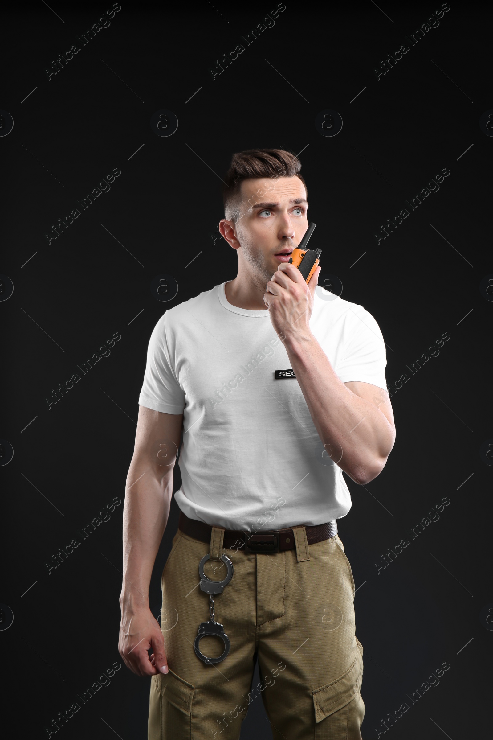 Photo of Male security guard using portable radio transmitter on dark background