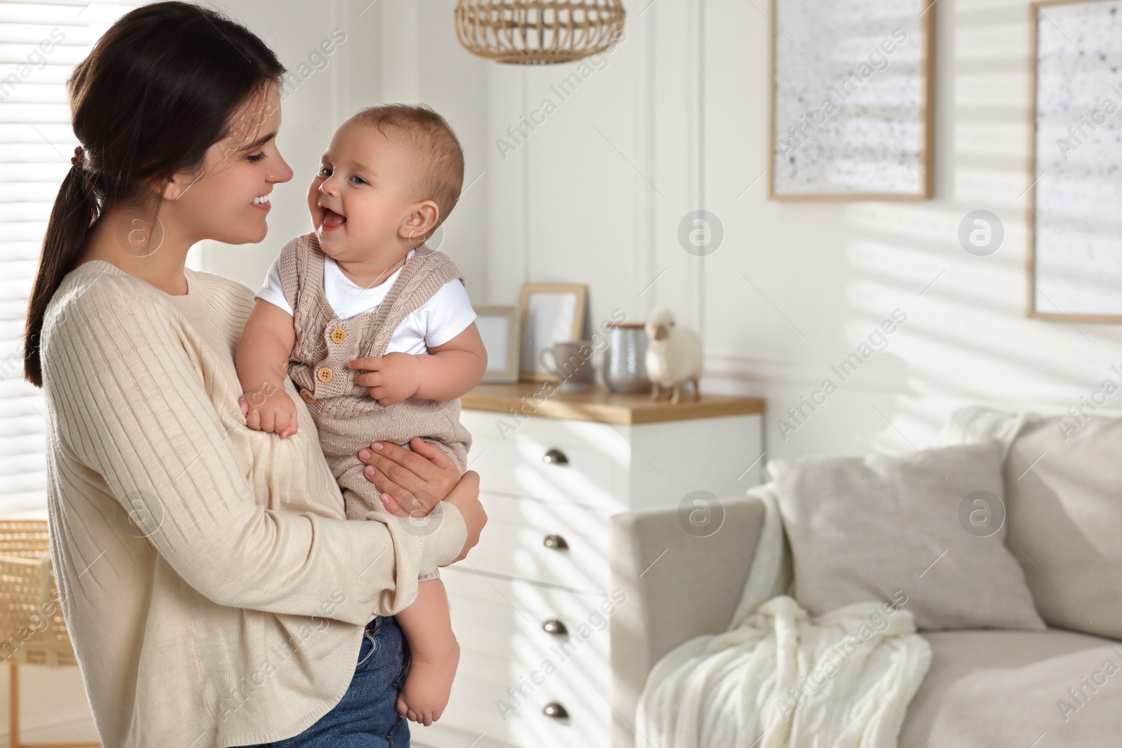 Photo of Happy young mother with her baby in living room. Space for text