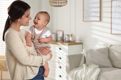 Photo of Happy young mother with her baby in living room. Space for text