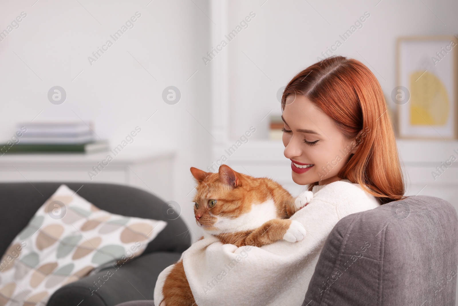 Photo of Happy woman with her cute cat in armchair at home. Space for text