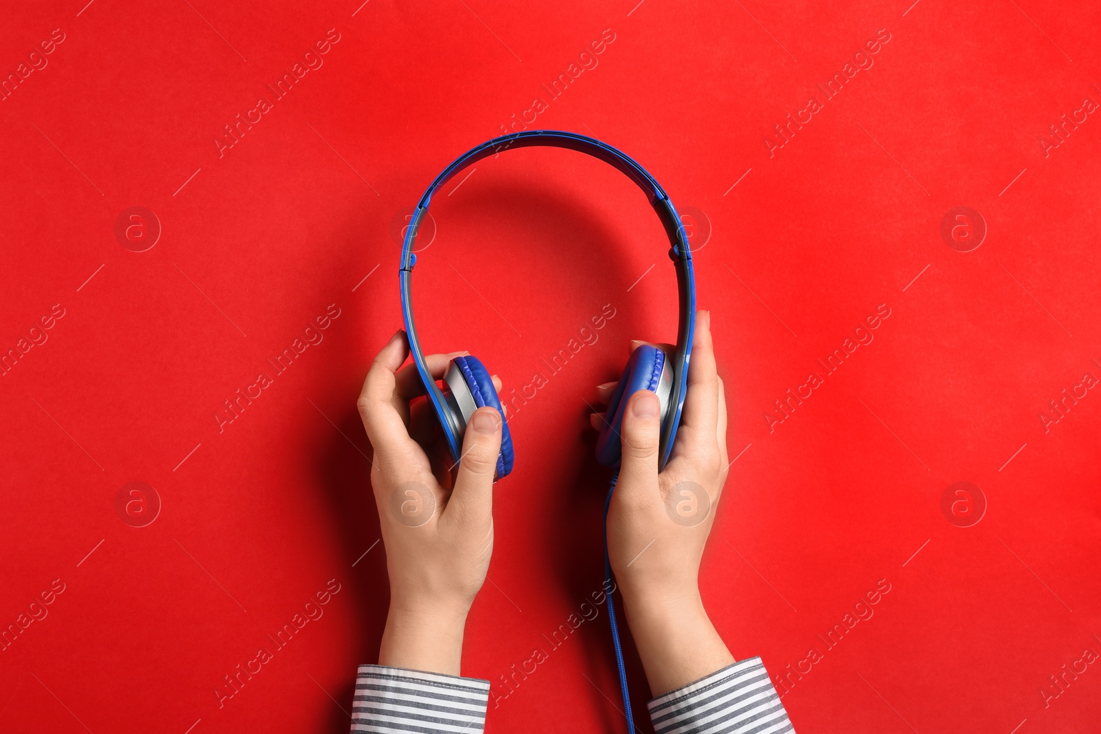 Photo of Woman holding stylish headphones on color background, closeup