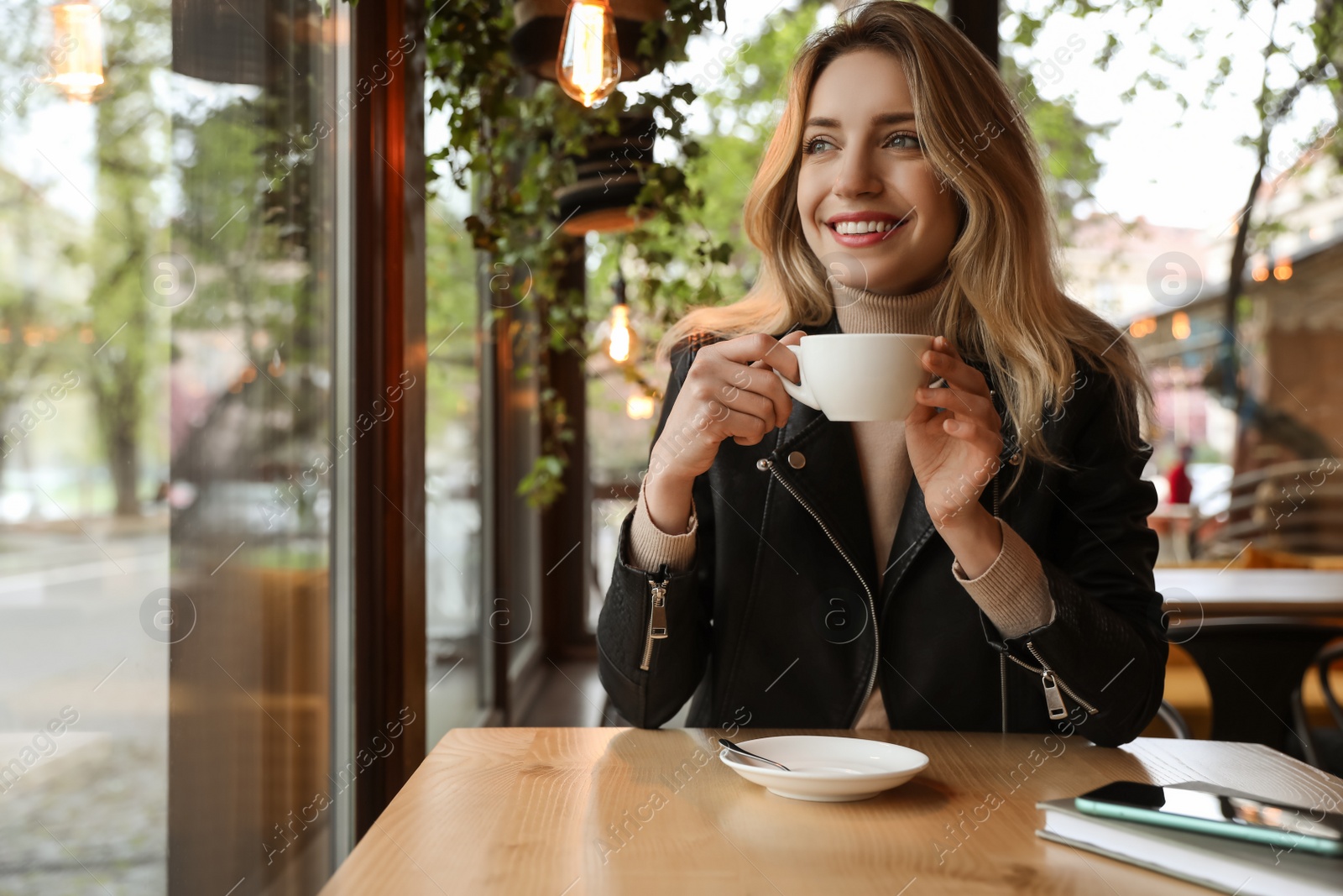 Photo of Young woman with cup of coffee at cafe in morning