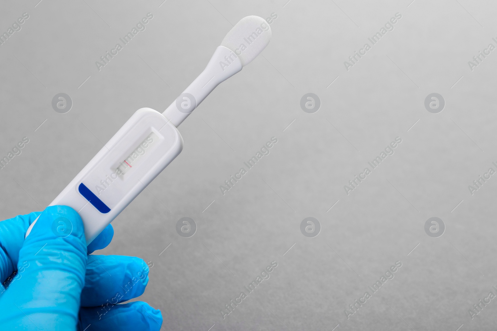 Photo of Doctor holding disposable express test on light grey background, closeup. Space for text