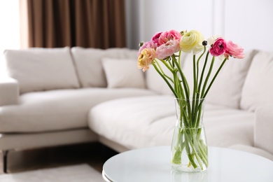 Photo of Beautiful ranunculus flowers on table in living room, space for text