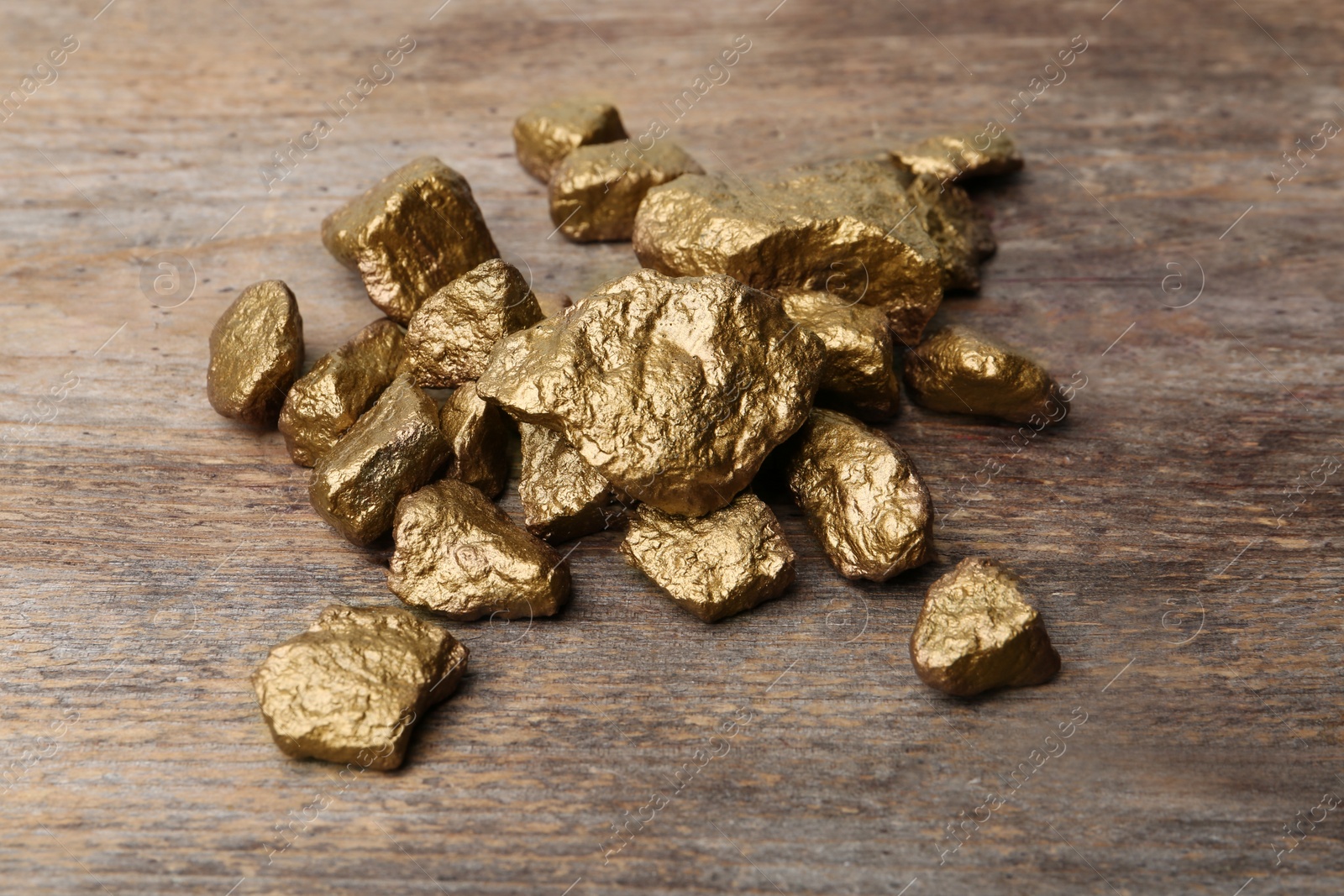 Photo of Pile of gold nuggets on wooden background