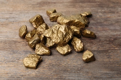 Photo of Pile of gold nuggets on wooden background