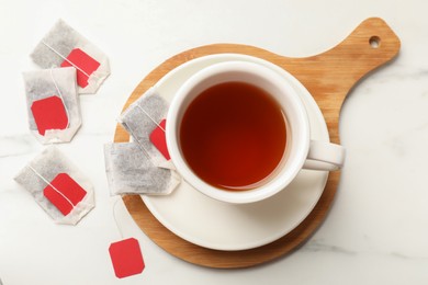 Photo of Tea bags and cup of hot beverage on white table, flat lay