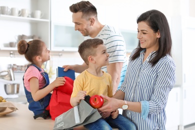 Young parents helping their little children get ready for school at home