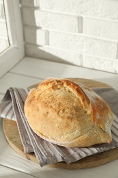 Photo of Freshly baked sourdough bread on white wooden table indoors