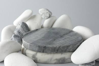 Photo of Presentation for product. Stone podium and pebbles on light grey background, closeup