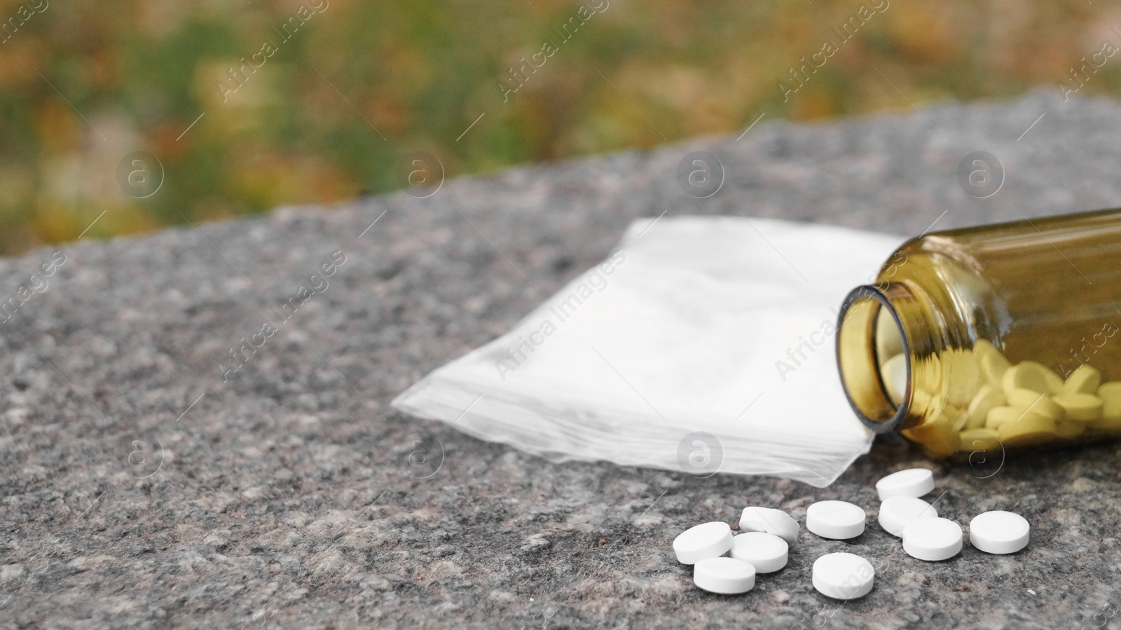 Photo of Plastic bag with powder, pills on stone surface outdoors, closeup and space for text. Hard drugs