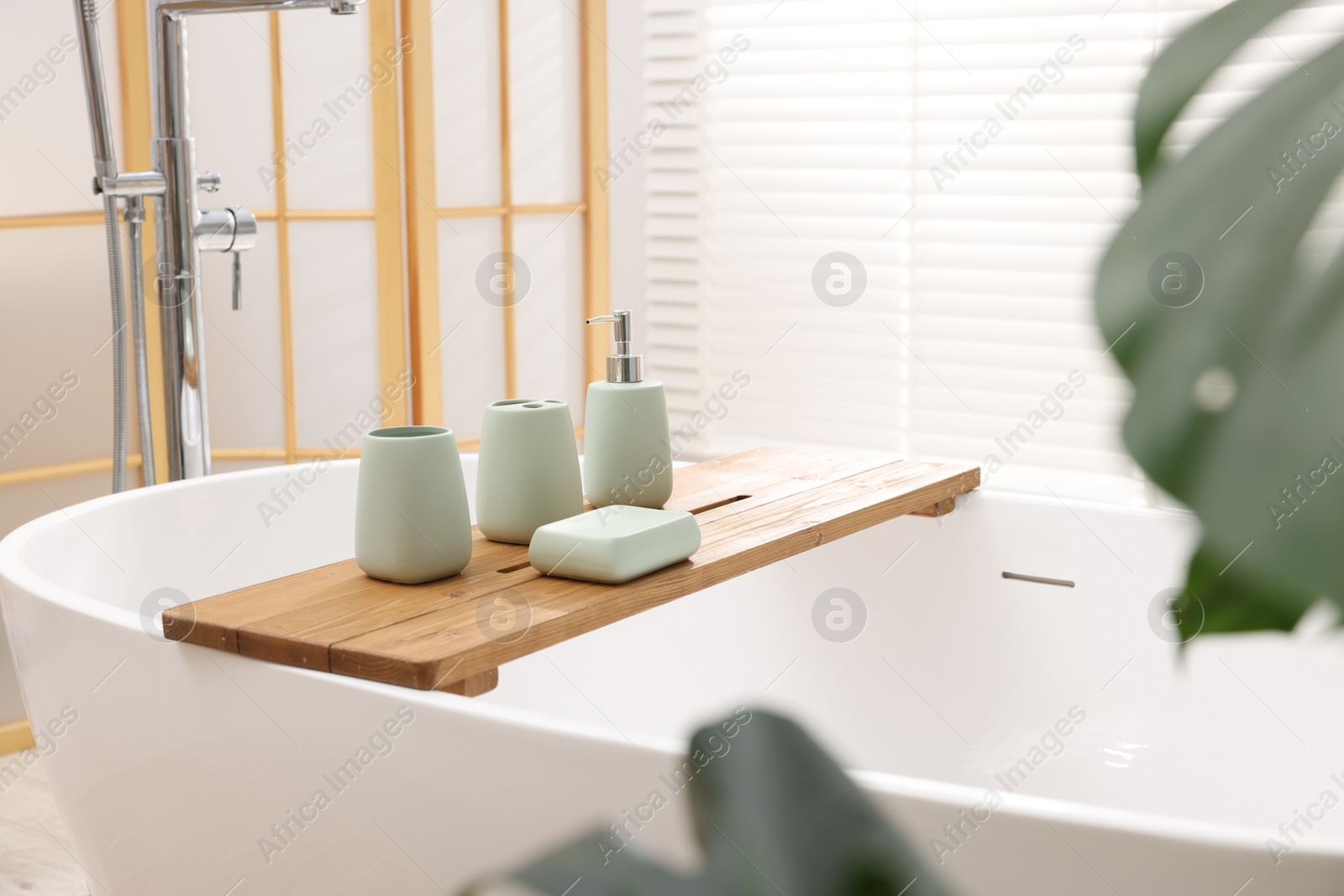 Photo of Set of bath accessories on tub in bathroom