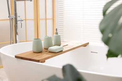 Photo of Set of bath accessories on tub in bathroom