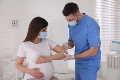 Photo of Doctor vaccinating pregnant woman against Covid-19 in clinic