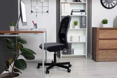 Stylish office interior with comfortable chair, desk and computer