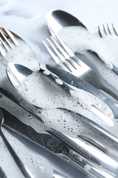Photo of Many forks, knives and spoons in foam, closeup