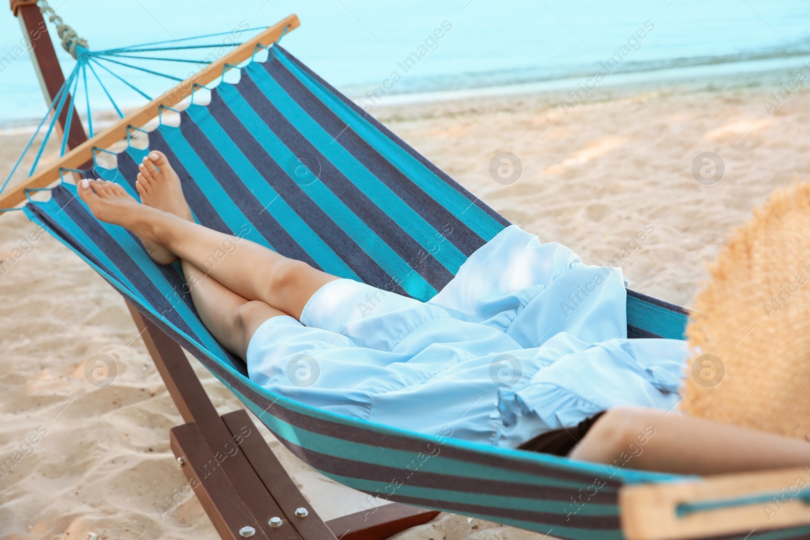 Photo of Young woman resting in comfortable hammock at seaside