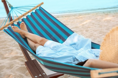 Young woman resting in comfortable hammock at seaside