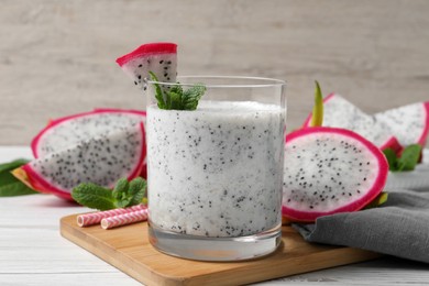 Glass of tasty pitahaya smoothie, dragon fruits and fresh mint on white wooden table