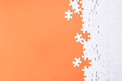 Blank white puzzle pieces on orange background, flat lay. Space for text