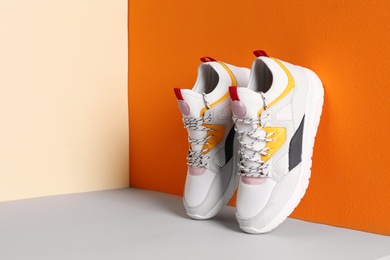 Photo of Pair of stylish sneakers near color wall, space for text