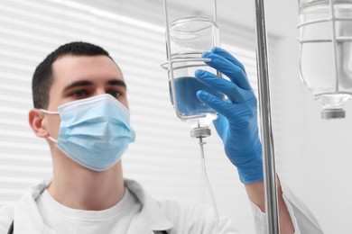 Photo of Doctor setting up IV drip in hospital, selective focus