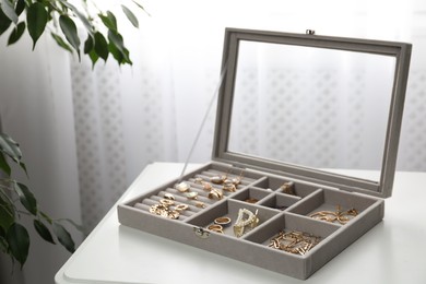 Photo of Elegant jewelry box with beautiful bijouterie on white table in room