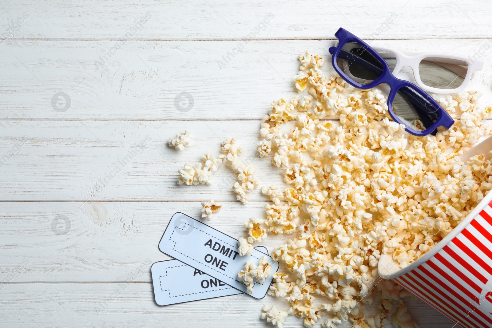 Photo of Bucket of fresh popcorn, tickets and 3D glasses on white wooden table, flat lay with space for text. Cinema snack