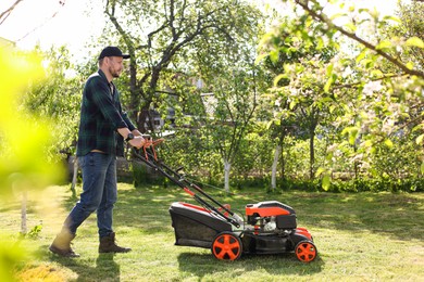 Man cutting green grass with lawn mower in garden