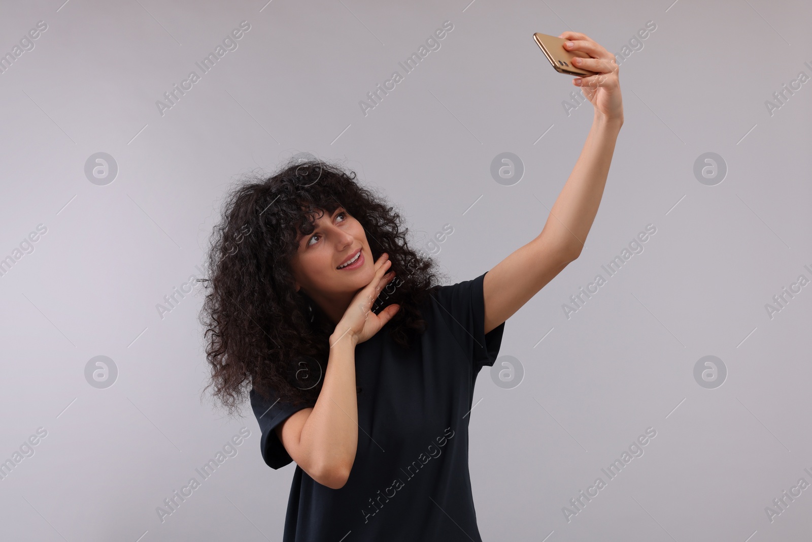 Photo of Beautiful young woman taking selfie on light grey background