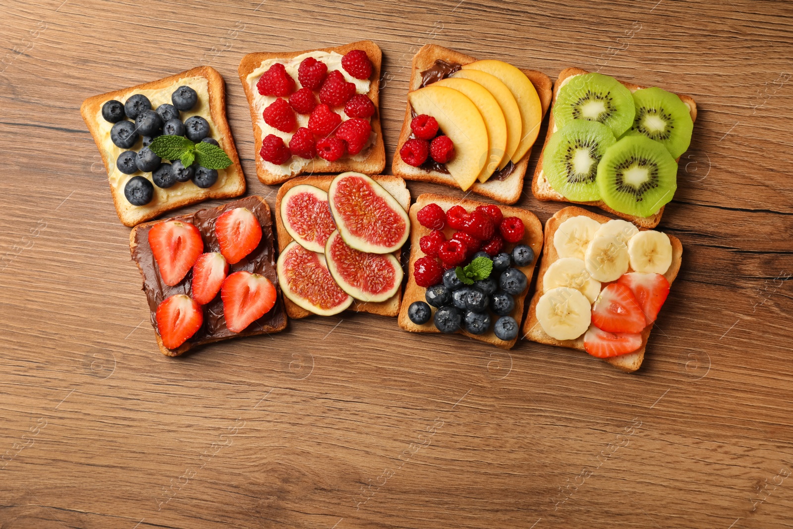 Photo of Tasty toasts with different spreads and fruits on wooden table, flat lay