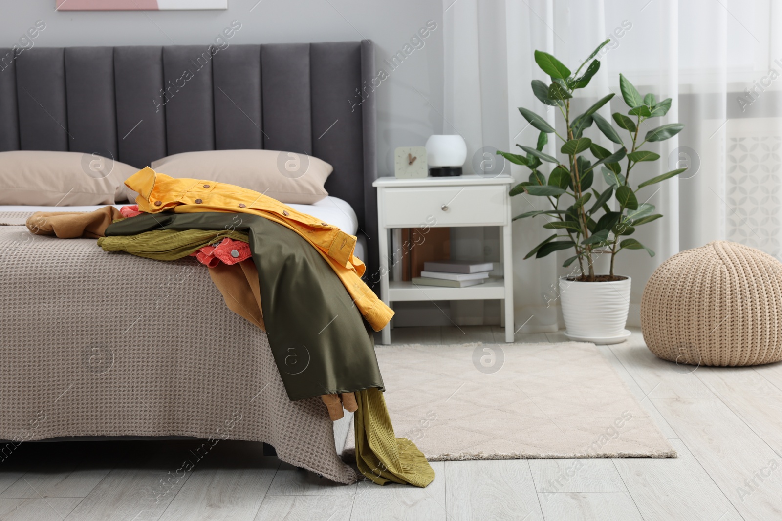 Photo of Pile of different clothes on bed at home