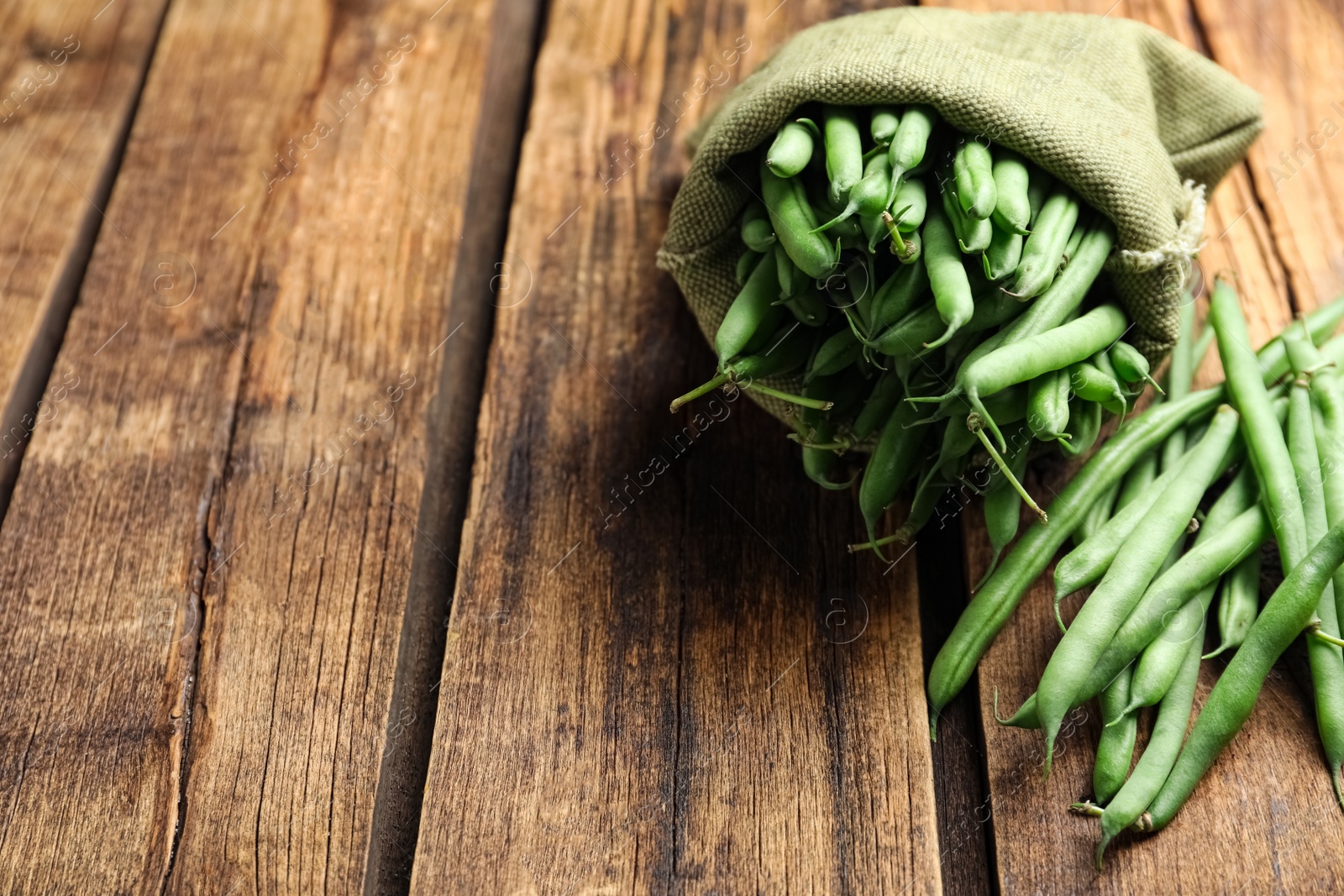 Photo of Fresh green beans on wooden table. Space for text