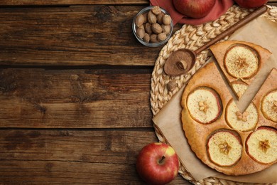 Tasty apple pie, nutmeg powder, seeds and fresh fruits on wooden table, flat lay. Space for text