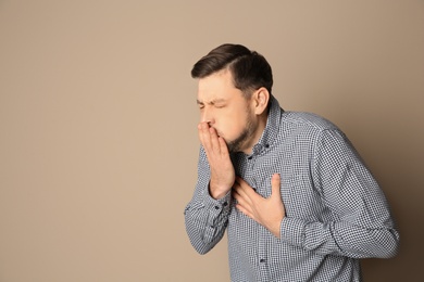 Man suffering from cough on color background. Space for text