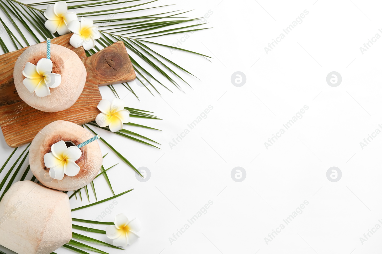 Photo of Fresh coconuts with drinking straws and flowers on white background, flat lay. Space for text