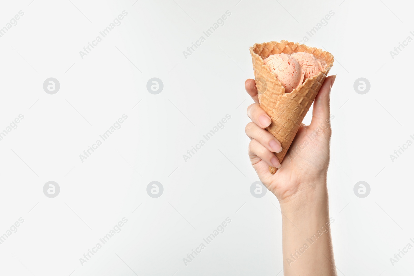 Photo of Woman holding delicious ice cream in waffle cone on white background, closeup