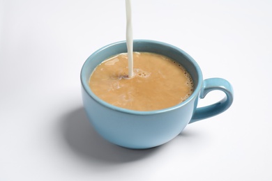 Photo of Pouring milk into cup of coffee on white background