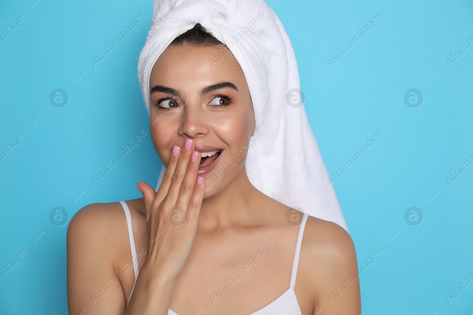 Photo of Beautiful young woman with towel on head against light blue background