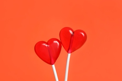 Photo of Sweet heart shaped lollipops on coral background, closeup. Valentine's day celebration