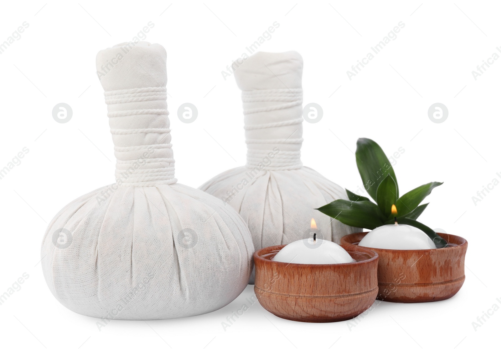 Photo of Herbal massage bags, green plant and candles on white background. Spa supply