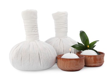 Photo of Herbal massage bags, green plant and candles on white background. Spa supply