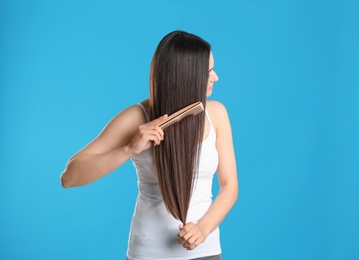 Photo of Beautiful young woman with hair comb on color background