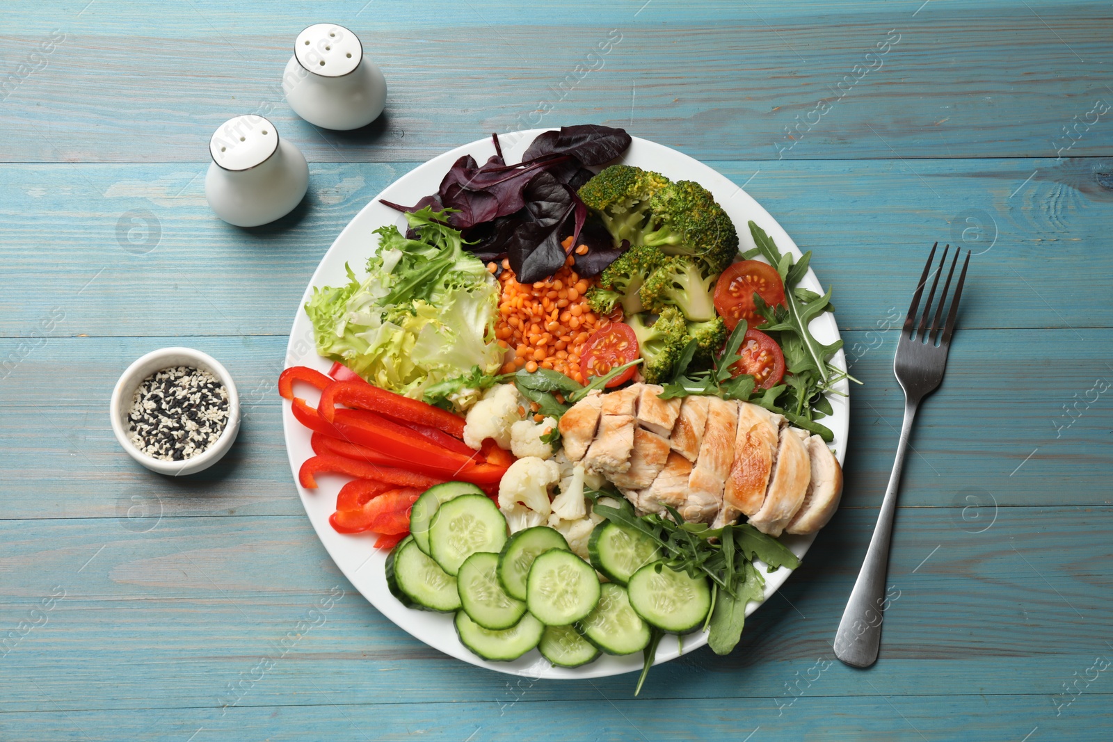 Photo of Balanced diet and healthy foods. Plate with different delicious products on light blue wooden table, flat lay