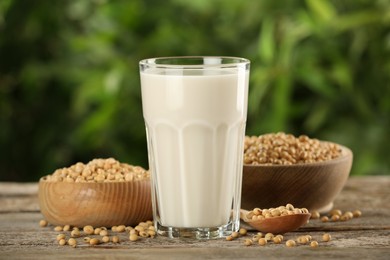 Photo of Glass with fresh soy milk and grains on white wooden table against blurred background