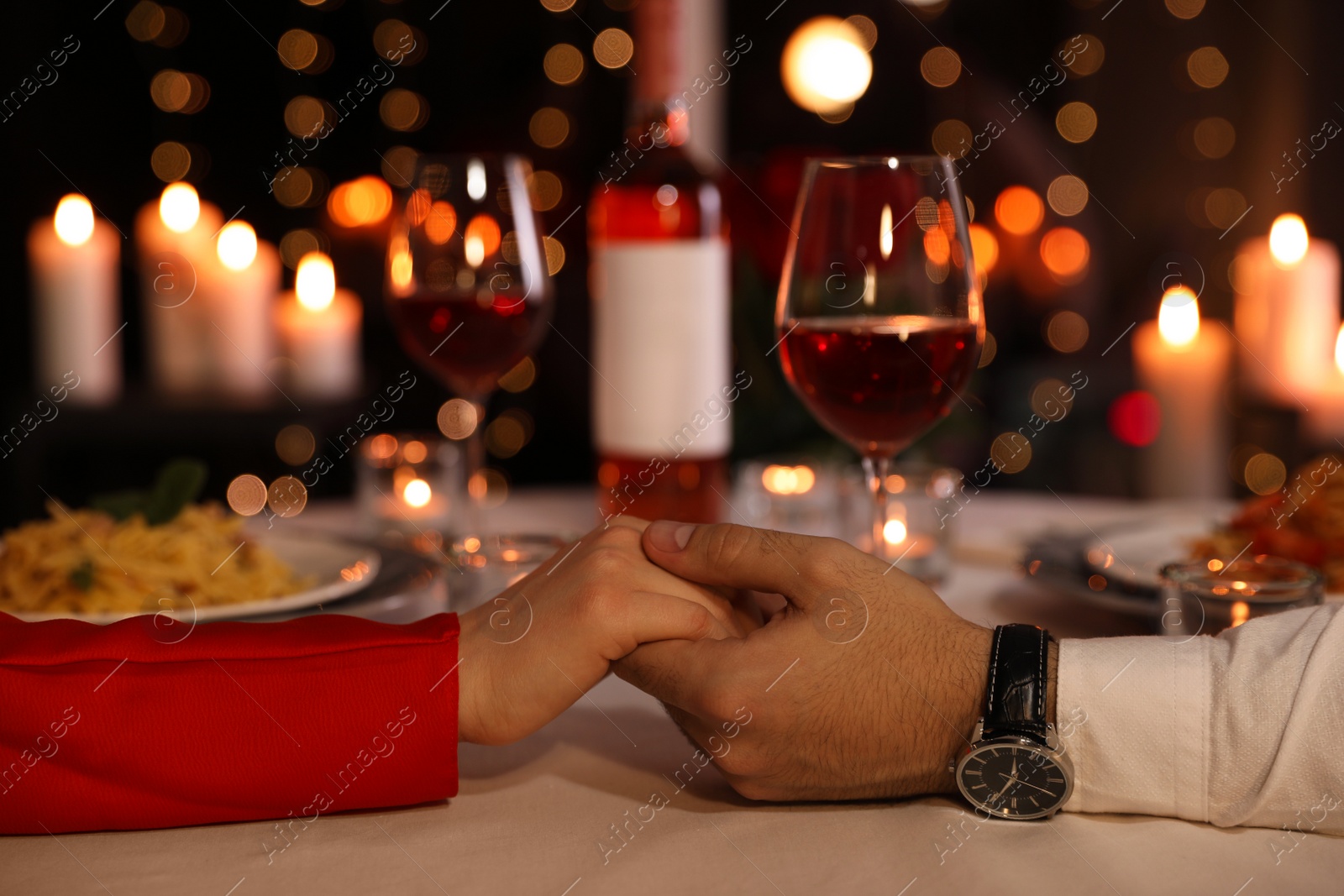 Photo of Couple holding hands together at table during romantic dinner in restaurant, closeup