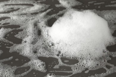 Photo of Fluffy bath foam on grey background, closeup view