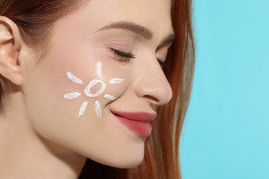 Photo of Beautiful young woman with sun protection cream on her face against light blue background, closeup. Space for text